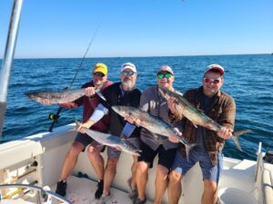 Four men on a fishing charter with their catch of king mackerel