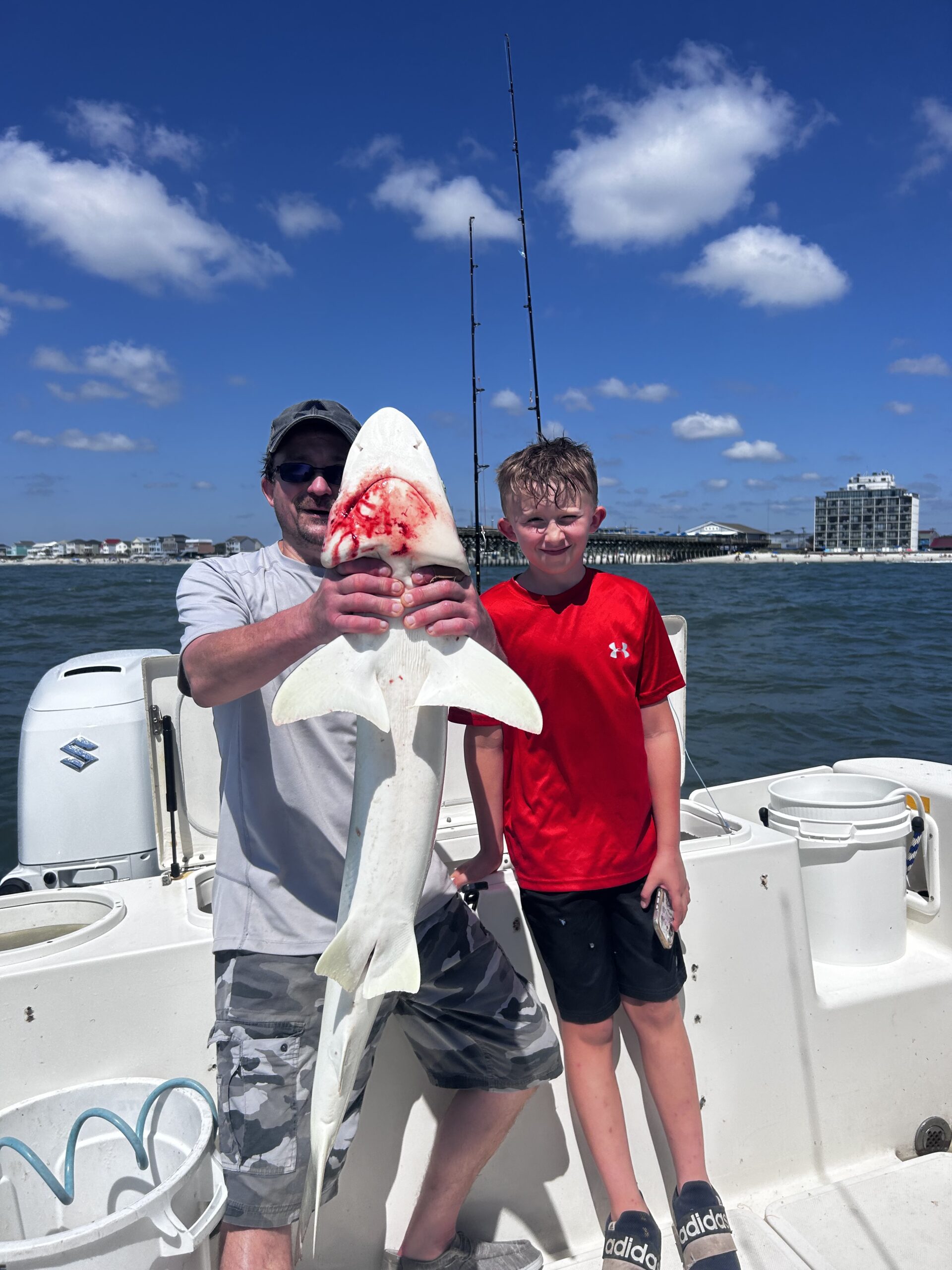 Father and son proudly display a small shark caught during a 4-hour reef fishing charter.